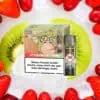 RandM Tornado Pods Strawberry Kiwi – grün-rote Verpackung mit Affen-Comic, sichtbarer Pod mit Totenkopf-Warnsymbol, platziert auf frischen Erdbeeren, Kiwi-Scheiben und Eiswürfeln